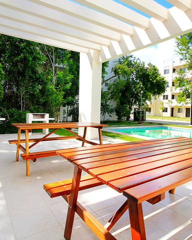 Covered patio with wooden picnic tables overlooking swimming pool and residential buildings