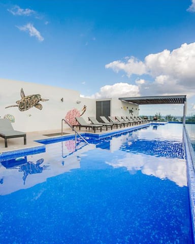 Rooftop infinity pool with blue water, lounge chairs, sea turtle mural, and panoramic landscape view