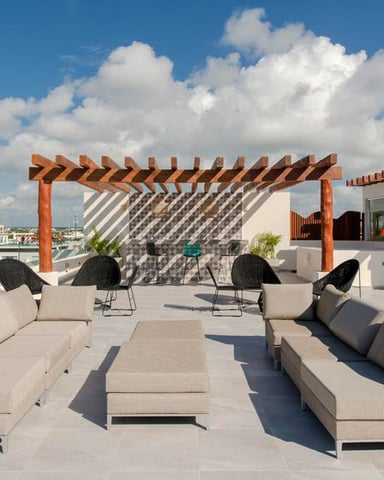 Rooftop terrace with modern seating, wooden pergola, and city skyline view under blue sky