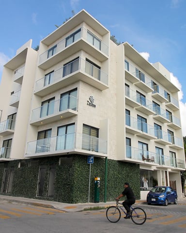 Modern six-story residential building with cream facade and balconies on urban street corner
