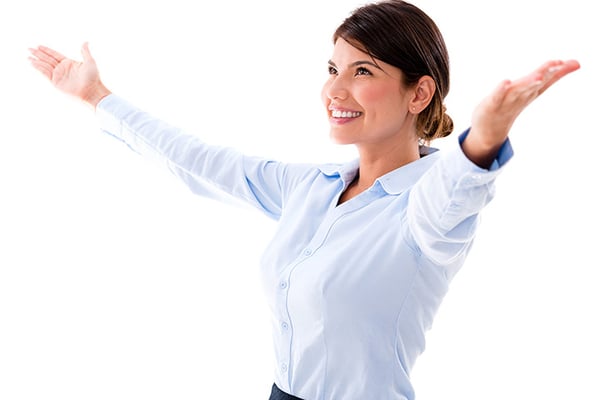 Woman in light blue button-up shirt with arms raised, smiling against white background